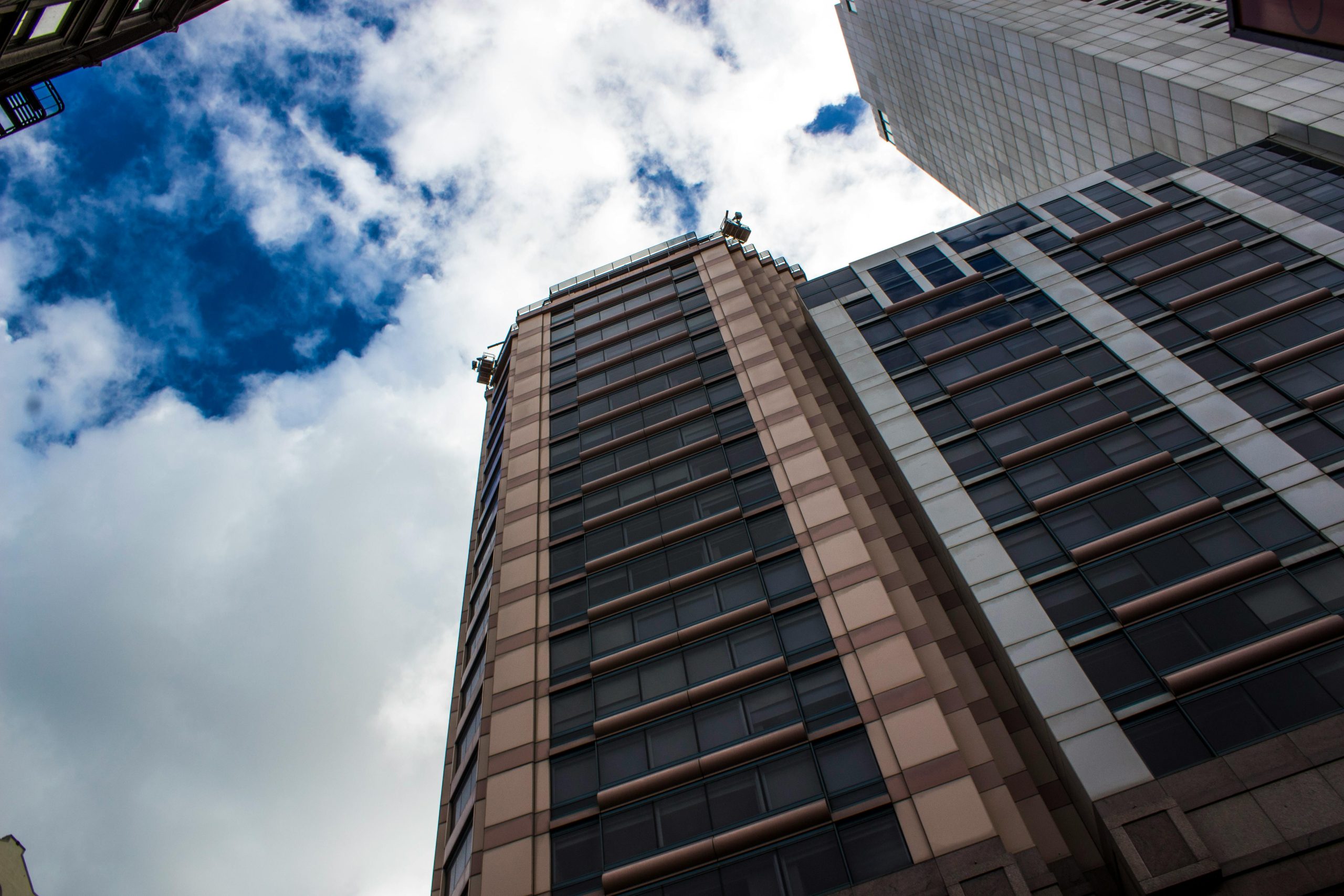 Low angle shot of modern skyscrapers in an urban setting against a cloudy sky.